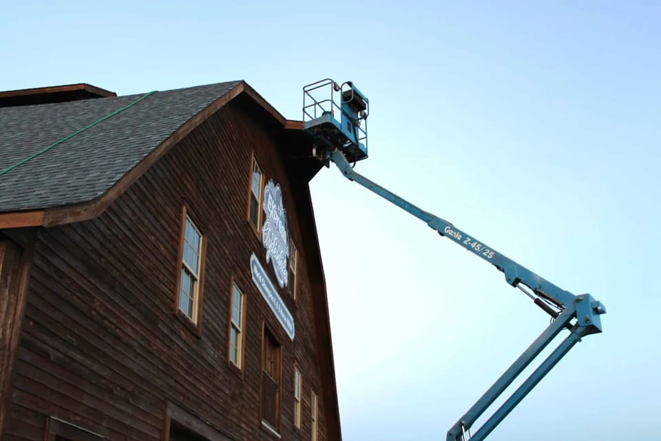 a boom lift being used to reach high places during the staining of the yukon, ok barns