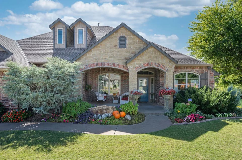 Stone-and-brick home on War Eagle Drive in Yukon, OK with a freshly painted exterior and manicured landscaping