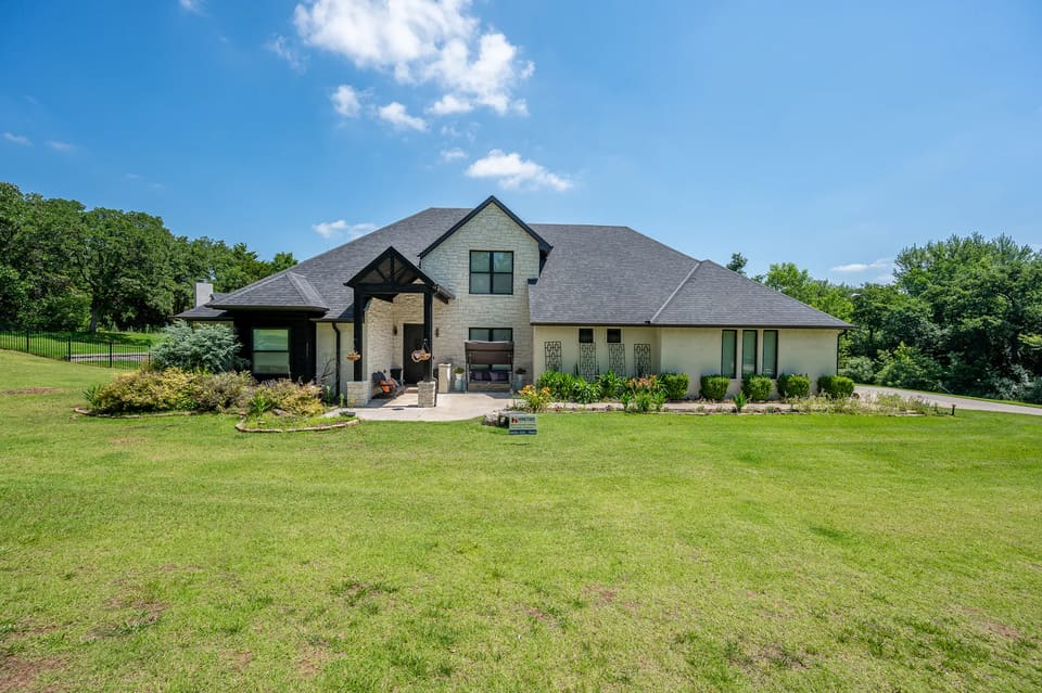 Stone and brick home on Lost Forest Drive in Edmond after being painted off-white with black trim by Hometown Painting