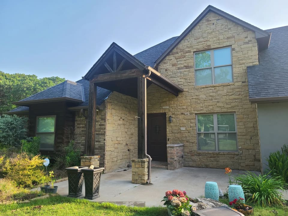 Before: tan stone and brick entryway with brown timber posts on the Newtons' Edmond home