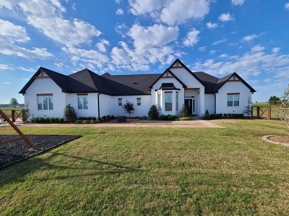 Large white painted-brick farmhouse-style home in the OKC metro