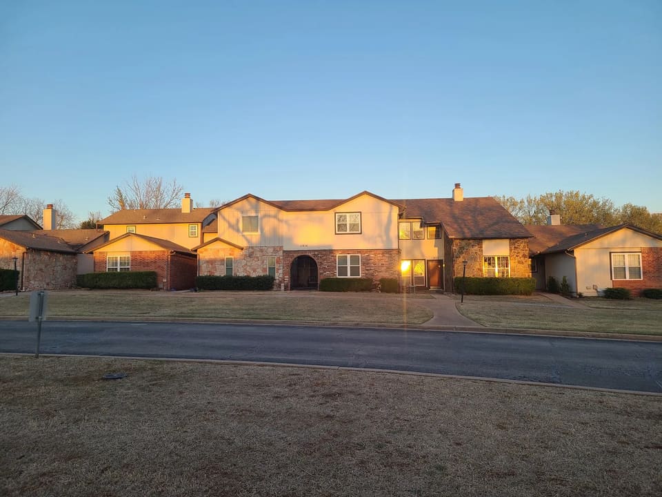 Before: a two-story townhome building at The Crossing in Edmond with faded tan siding and worn trim