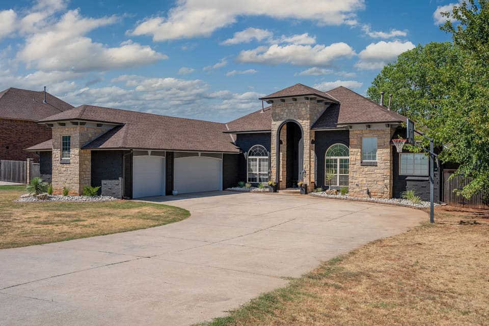 Edmond, OK home with brick painted a deep charcoal black, natural stone towers left unpainted, and cream trim