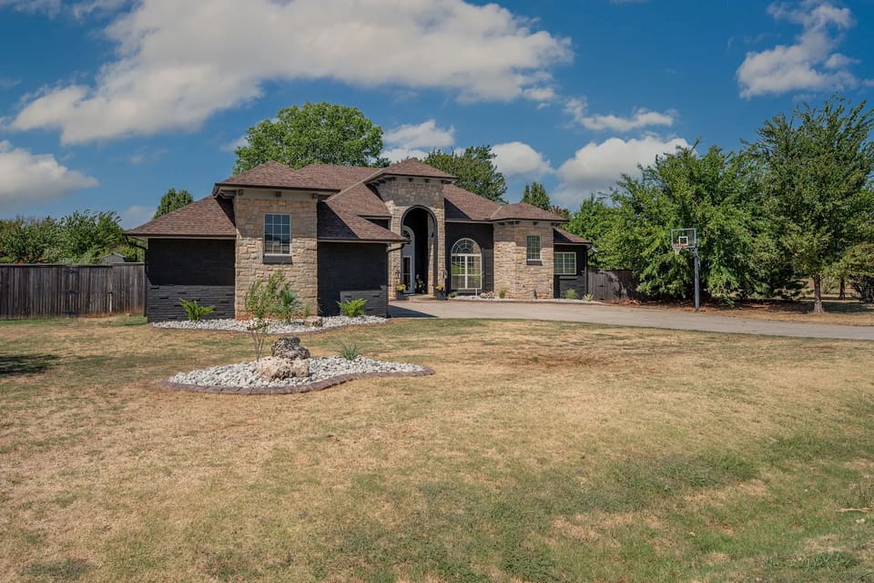 Angled view of the Edmond home showing Celtic Stone painted brick, unpainted stone towers, and fresh landscaping