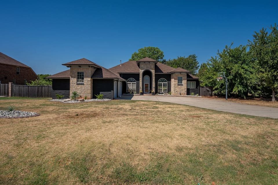 Stone and brick home in Edmond, OK after the brick was painted Celtic Stone, a deep charcoal black, with the natural stone towers left unpainted