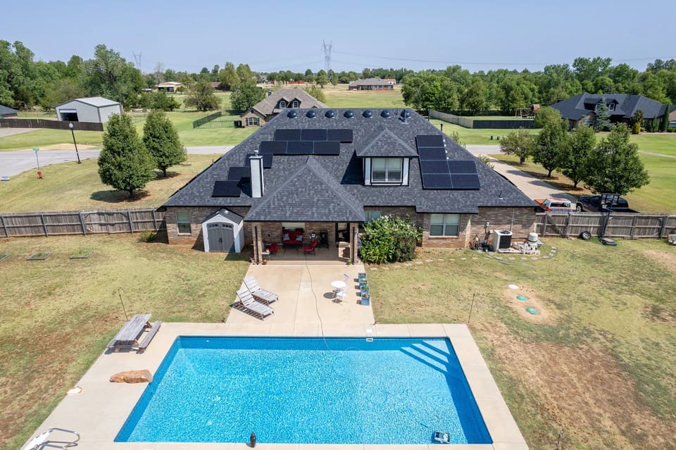 Aerial view of a Yukon, OK brick home showing the rear rooflines Hometown Painting worked around, with solar panel arrays beside the chimney