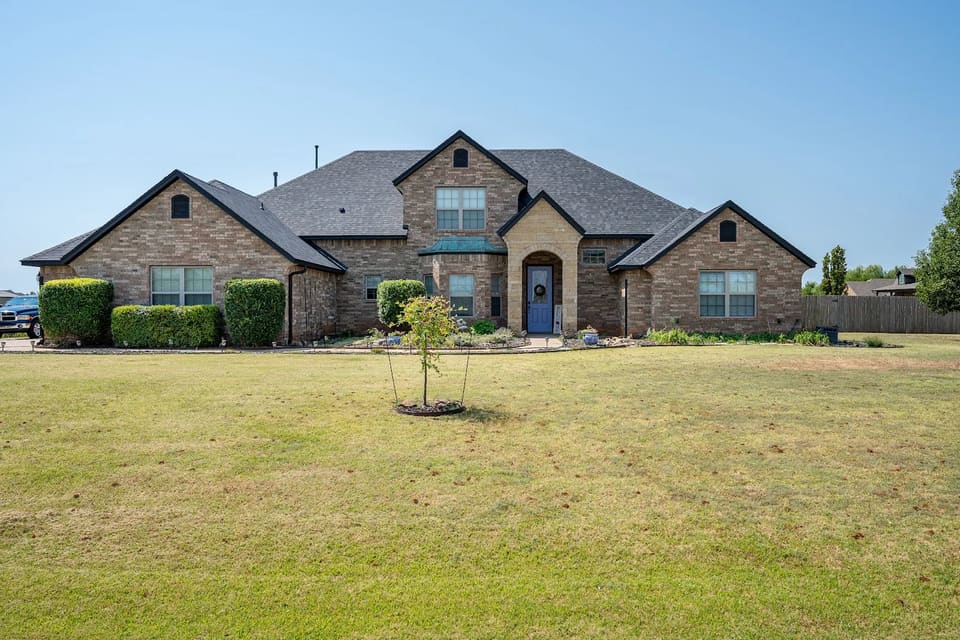 Brick home in Yukon, OK after an exterior repaint by Hometown Painting, with Iron Ore painted fascia, gables and trim under a new dark roof