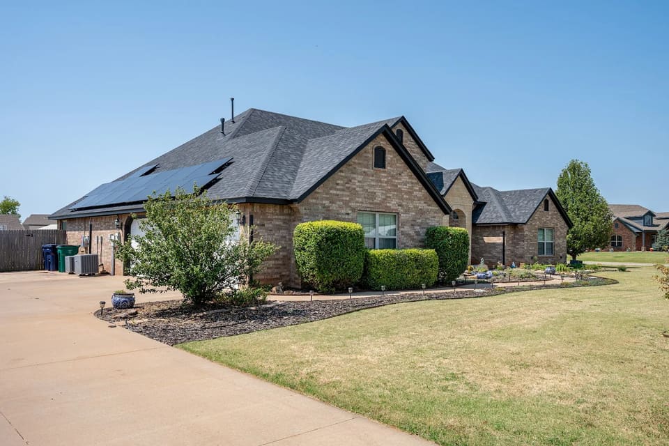 Side view of the Yukon home showing crisp Iron Ore fascia and roofline trim above the original blonde brick